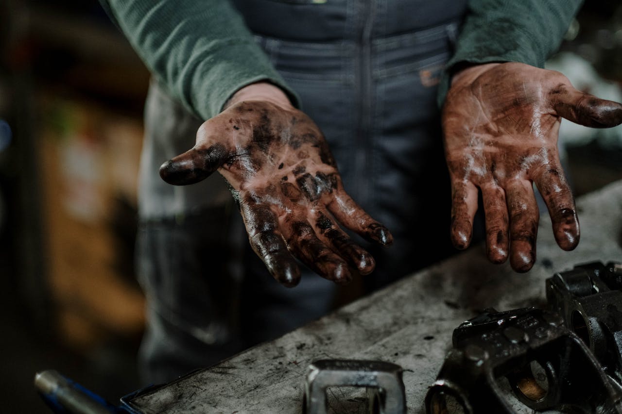Close-up of a mechanics dirty hands in a garage workspace with grease and spare parts.