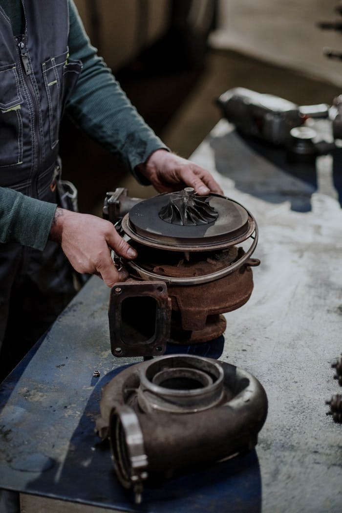 Mechanic working on a turbocharger assembly in a repair shop setting.